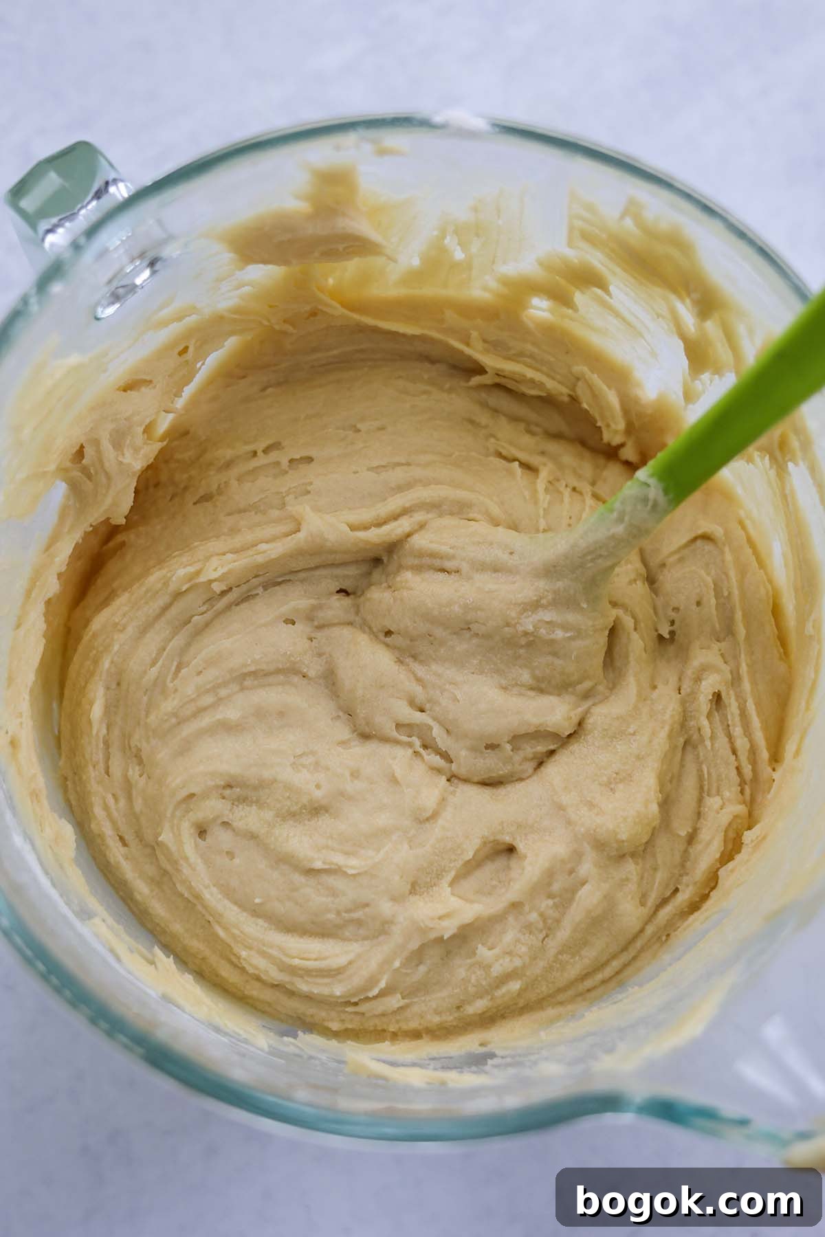 cake batter in a glass bowl with a rubber spatula.