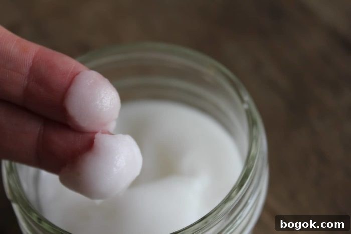 15 DIY Skincare Products You Can Make at Home to Cut Costs 13 Image shows a small jar with two fingers holding homemade face cream