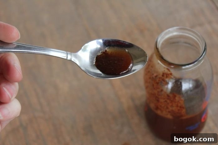 15 DIY Skincare Products You Can Make at Home to Cut Costs 9 Image shows a spoon over a small jar holding homemade cough syrup
