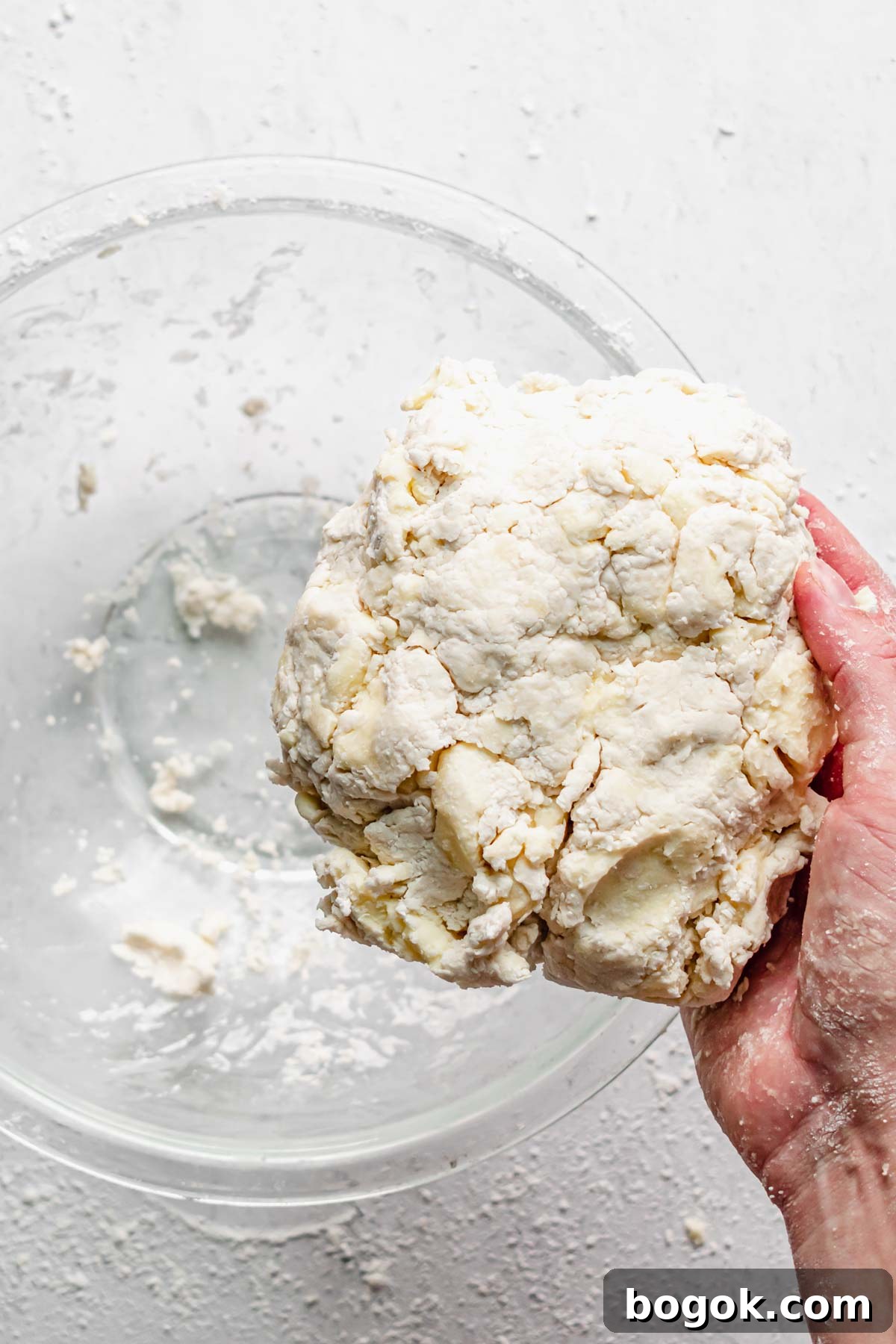 A hand holds the dough in a form.
