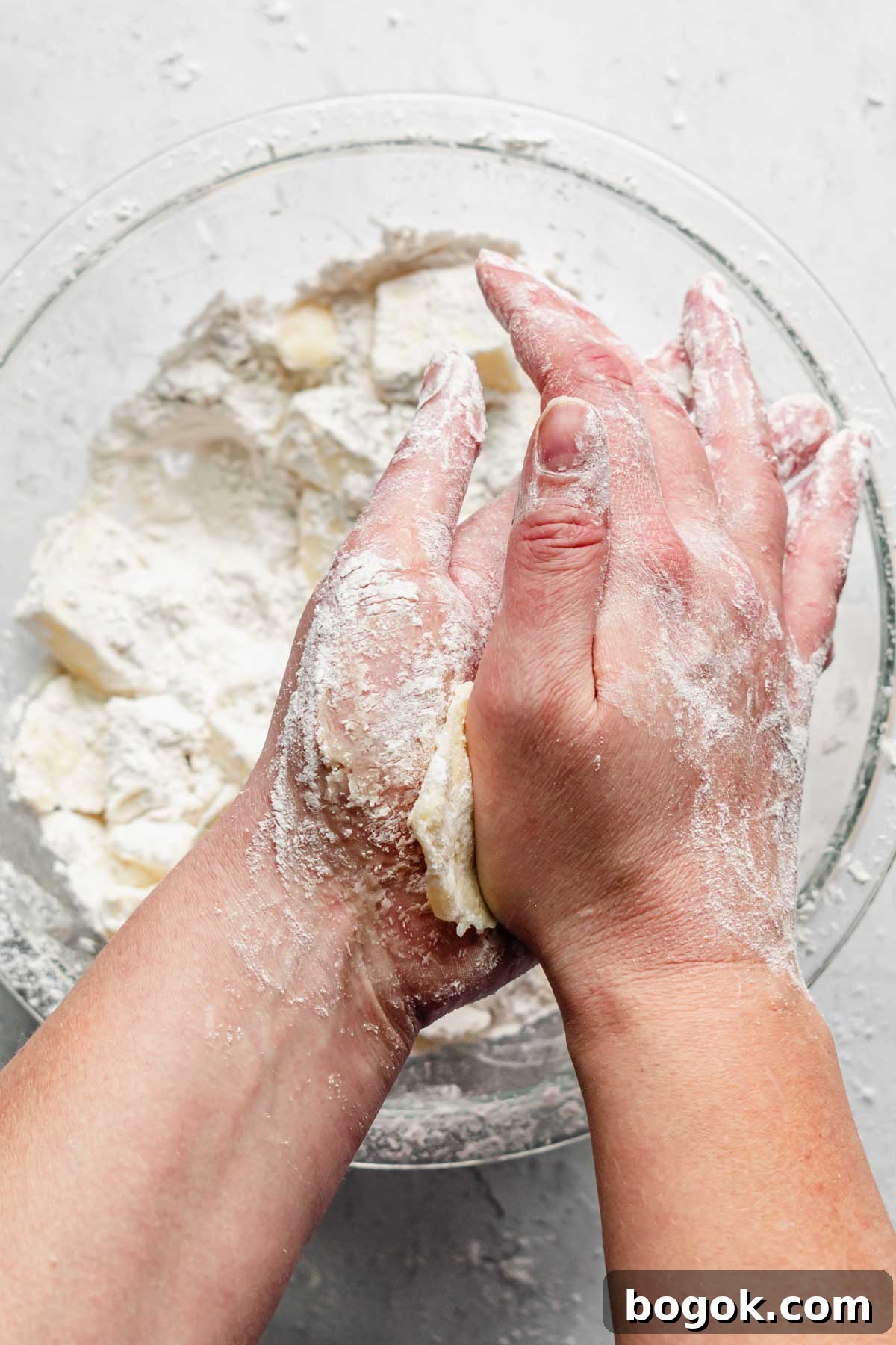 Flattening butter between the palms of two hands.