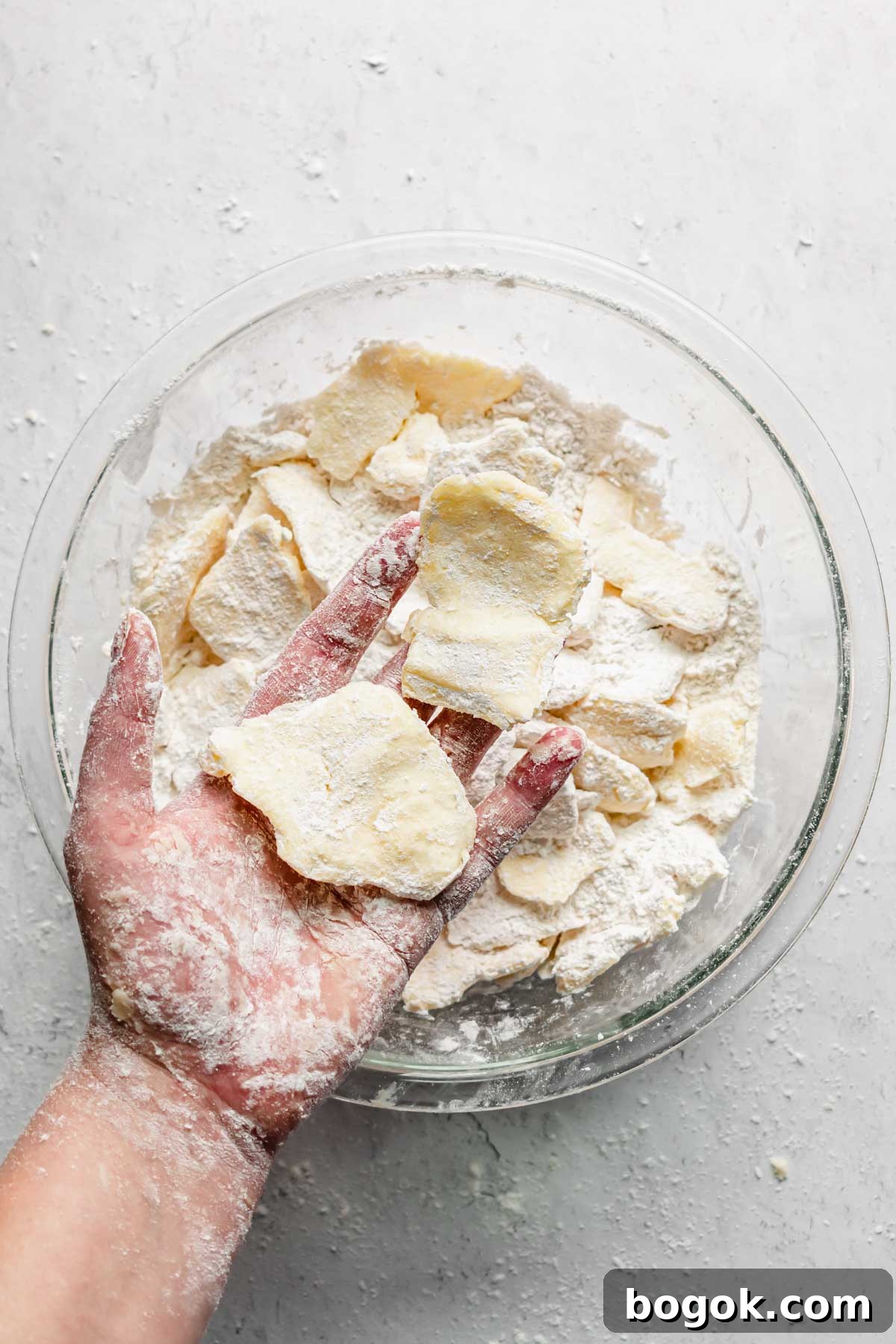 A hand holds two pieces of flattened butter.