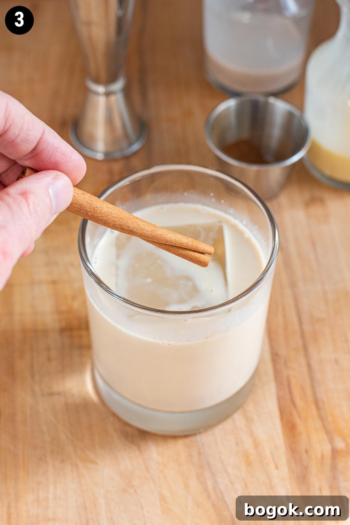 Creamy Eggnog Cocktail Recipe for Holiday Parties 6 Adding a cinnamon stick garnish to an eggnog cocktail.