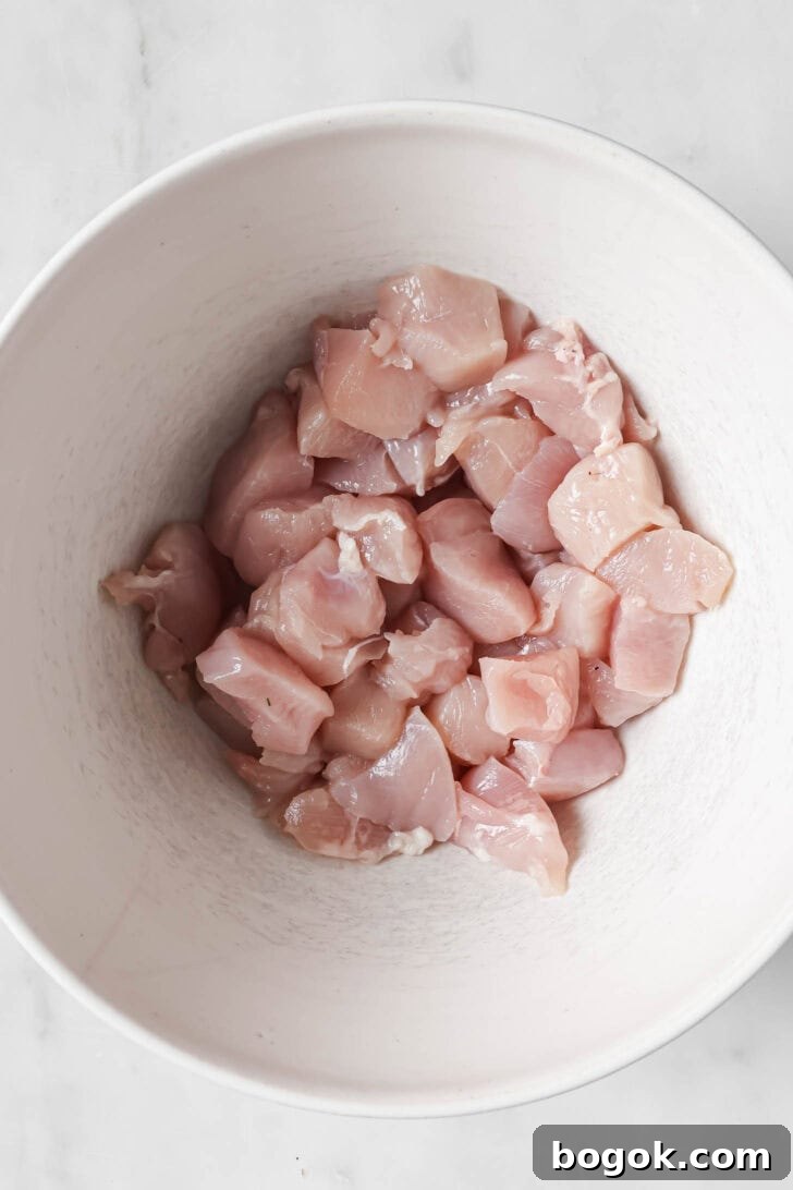 Cubed chicken in a bowl ready to be marinated to make Honey Ginger Chicken.