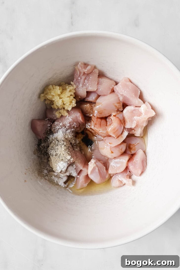 Chicken in a bowl with marinade ingredients.