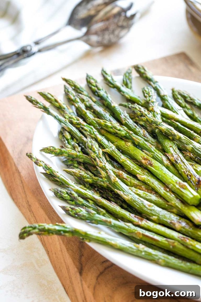 Partial view of the top portion of the roasted asparagus spears after they're out of the oven and pile on a white serving platter.