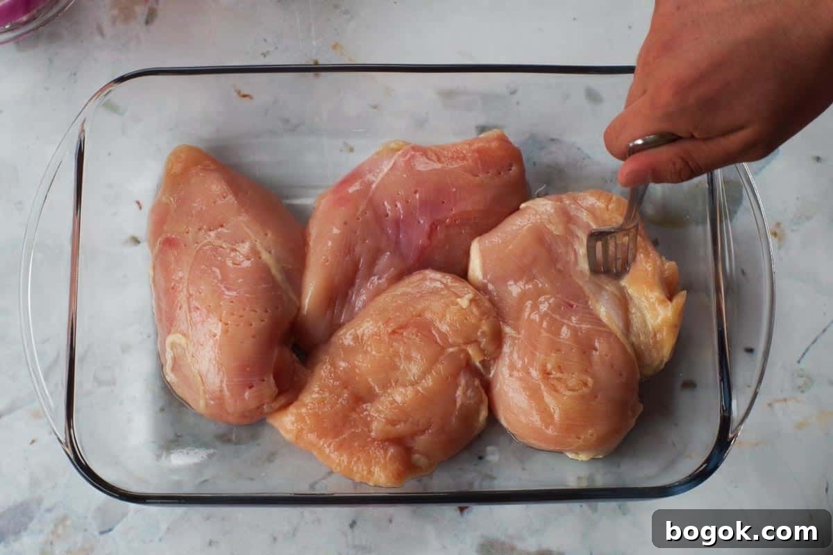 Greek Chicken Souvlaki Without Skewers — Weight Watchers Recipe 5 Raw chicken breasts in a glass container being scored with a fork.