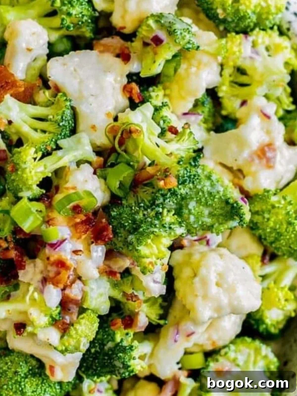 picture of broccoli and cauliflower salad in a speckled bowl with bacon and peas