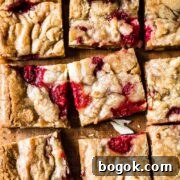 Raspberry White Chocolate Blondies Recipe with Crispy Edges 13 Raspberry white chocolate blondies on a wooden cutting board.