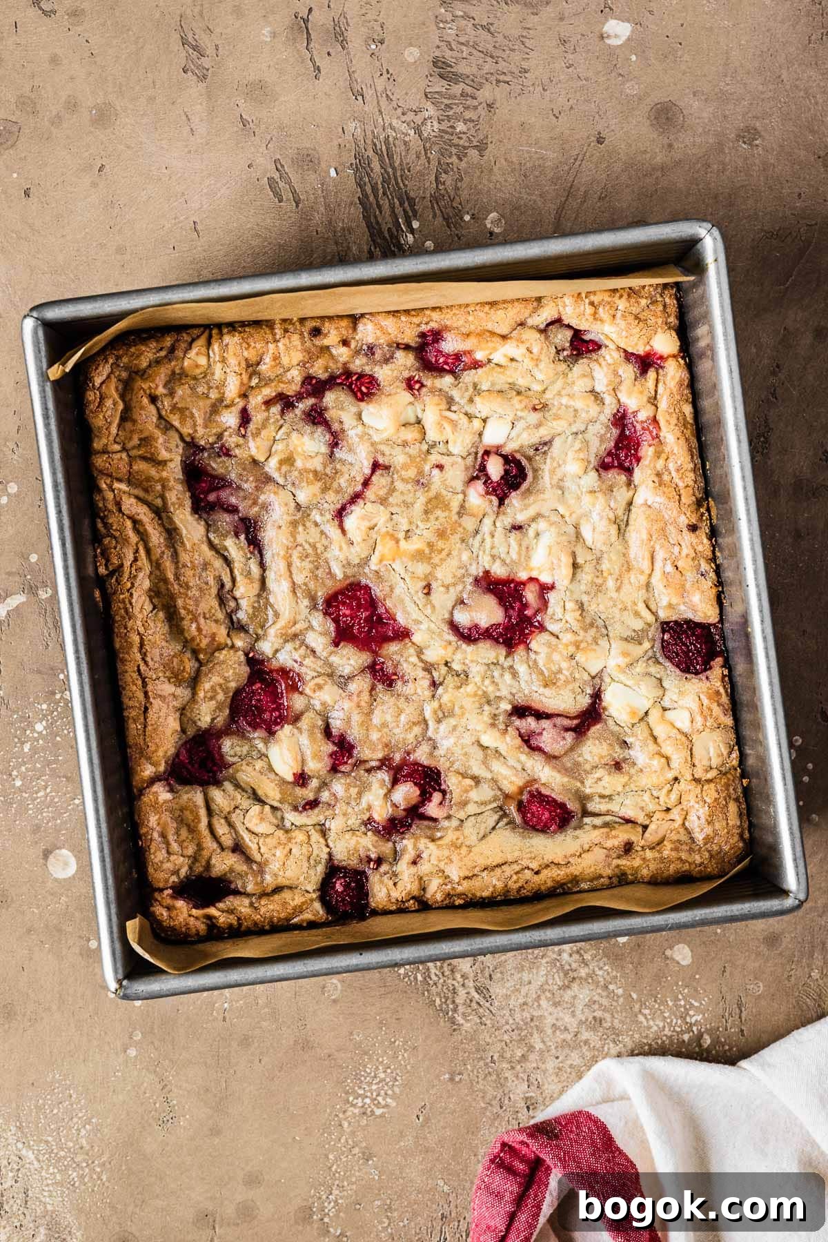 Raspberry White Chocolate Blondies Recipe with Crispy Edges 9 A square pan of baked rasberry blondies that have not yet been cut.