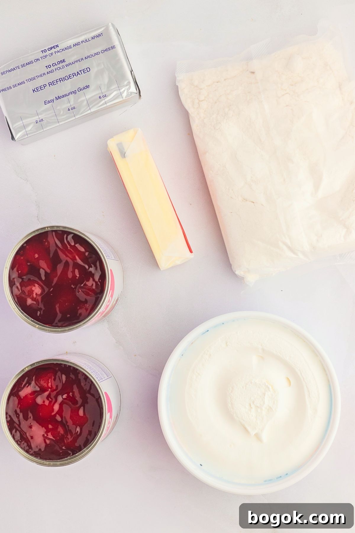 Ingredients needed to make strawberry dump cake on a white marble table. 