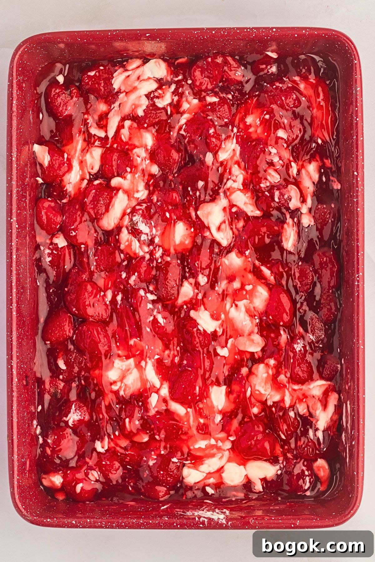 Strawberry pie filling, cream cheese combined in a cake pan. 