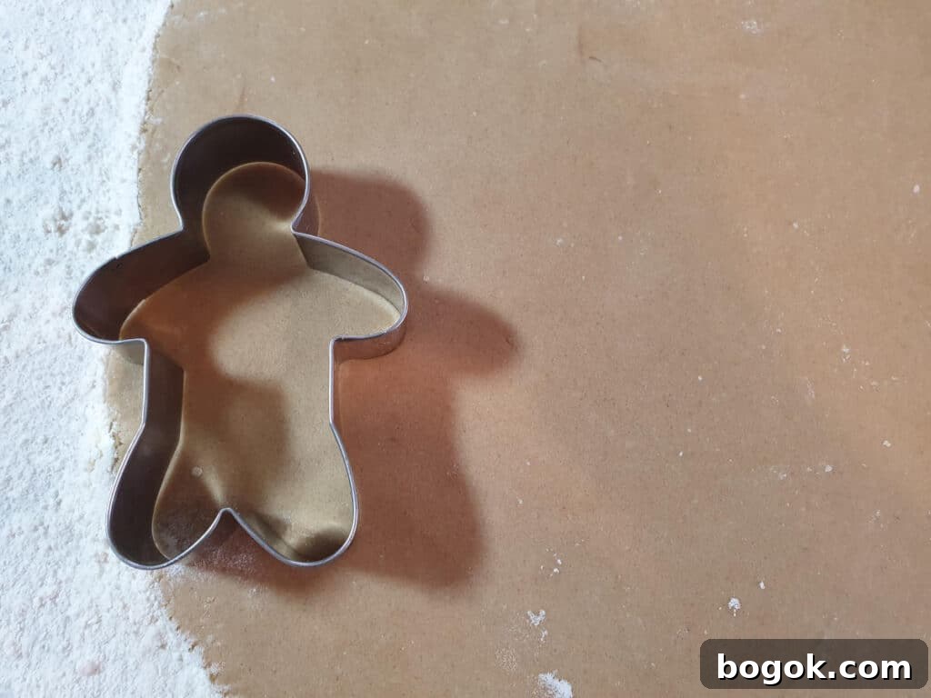 cutting gingerbread men shapes out of rolled out dough.