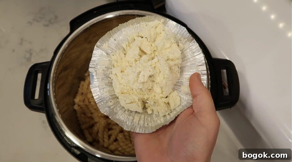 Garlic Herb Cheese Pasta Made in the Instant Pot 8 Adding garlic herb cheese to pot