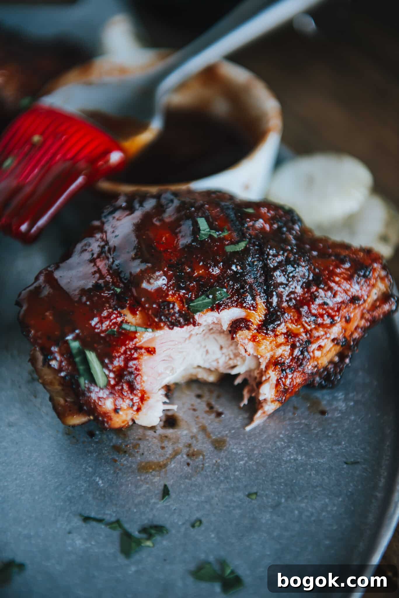 Close up of a smoked chicken thigh with a bite taken out of it.