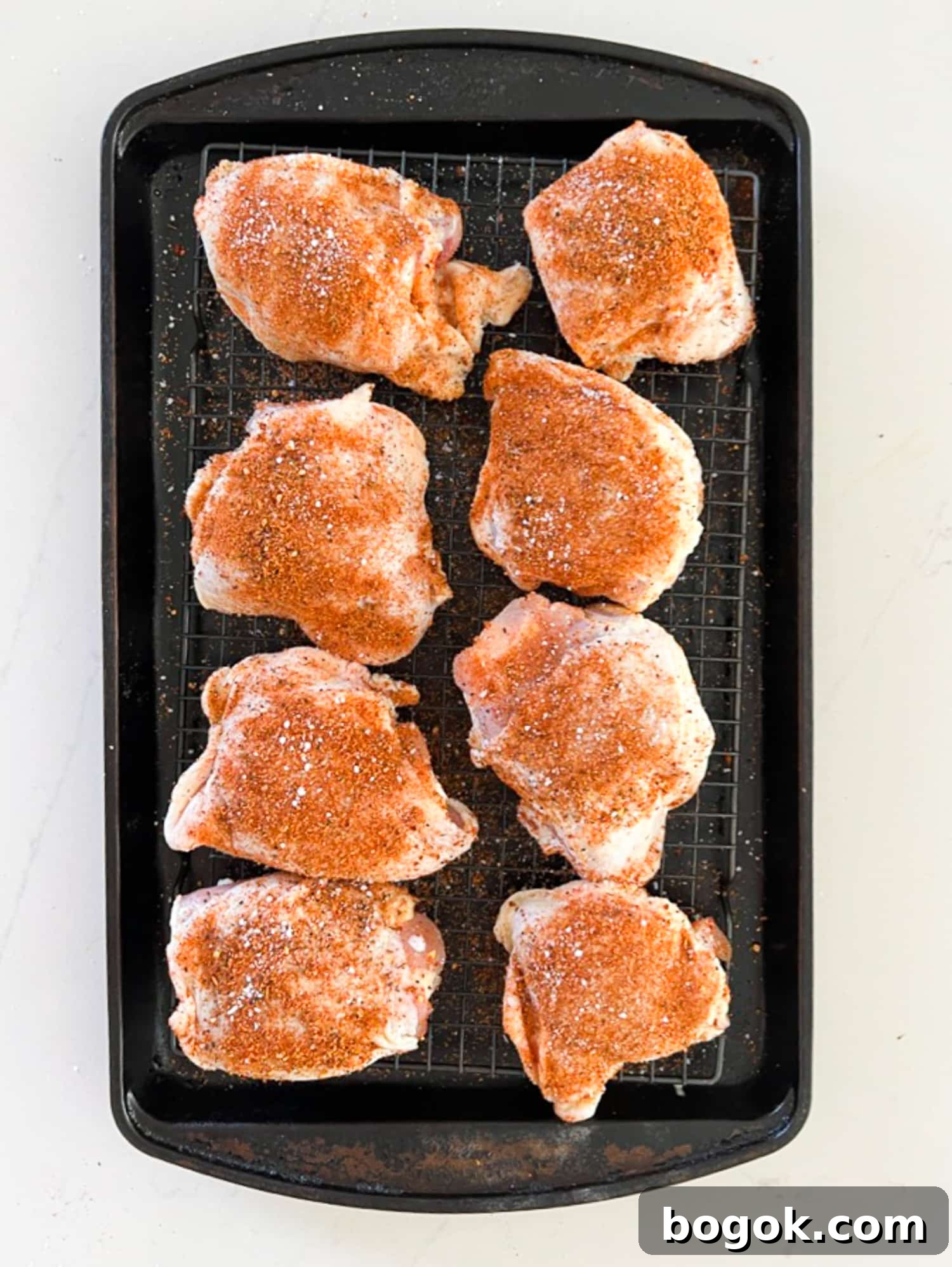 Raw chicken thighs coated with spices.