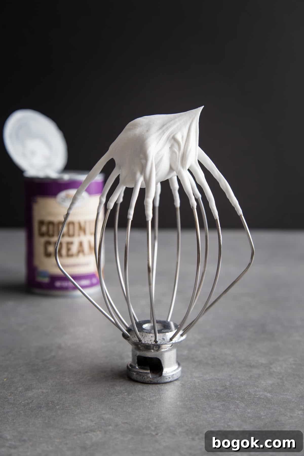 Whipped coconut cream with stiff peak on a wire whip.