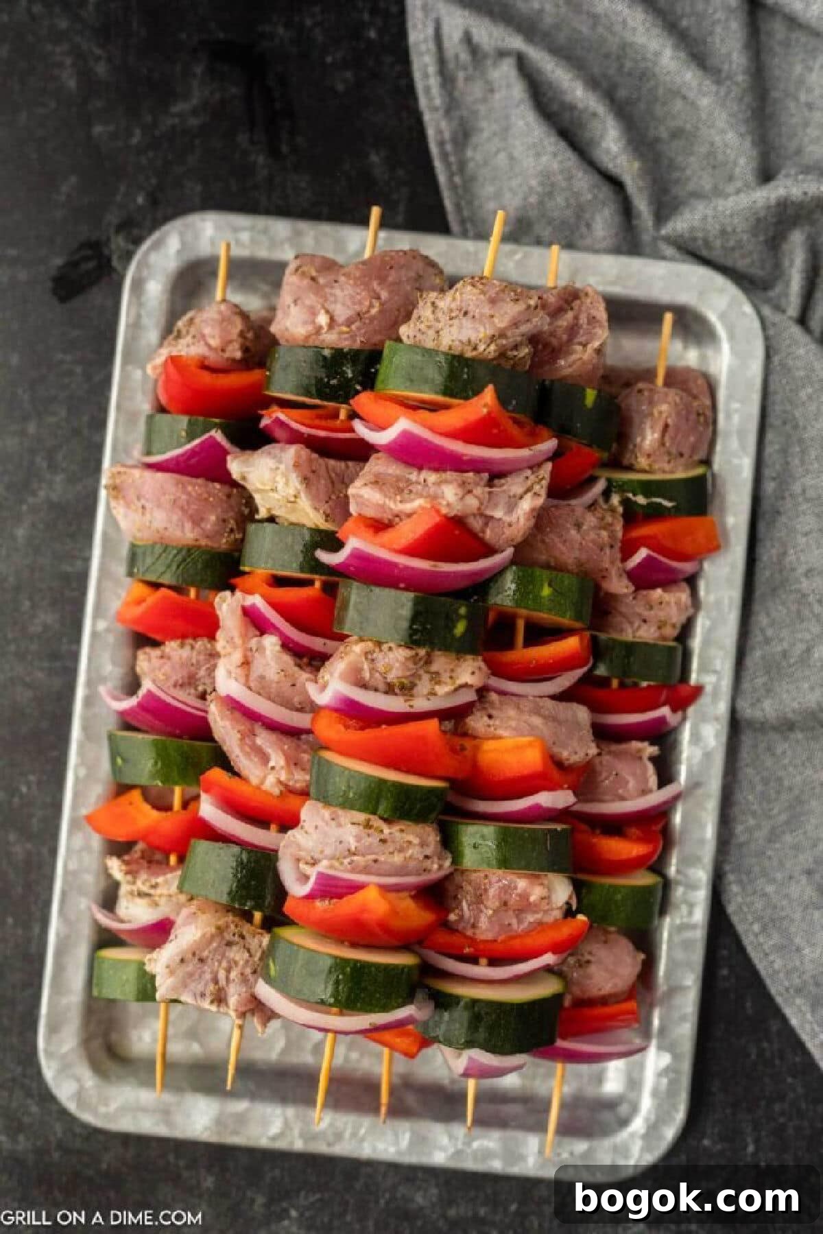 Uncooked Pork and veggie kabobs stacked on a metal platter