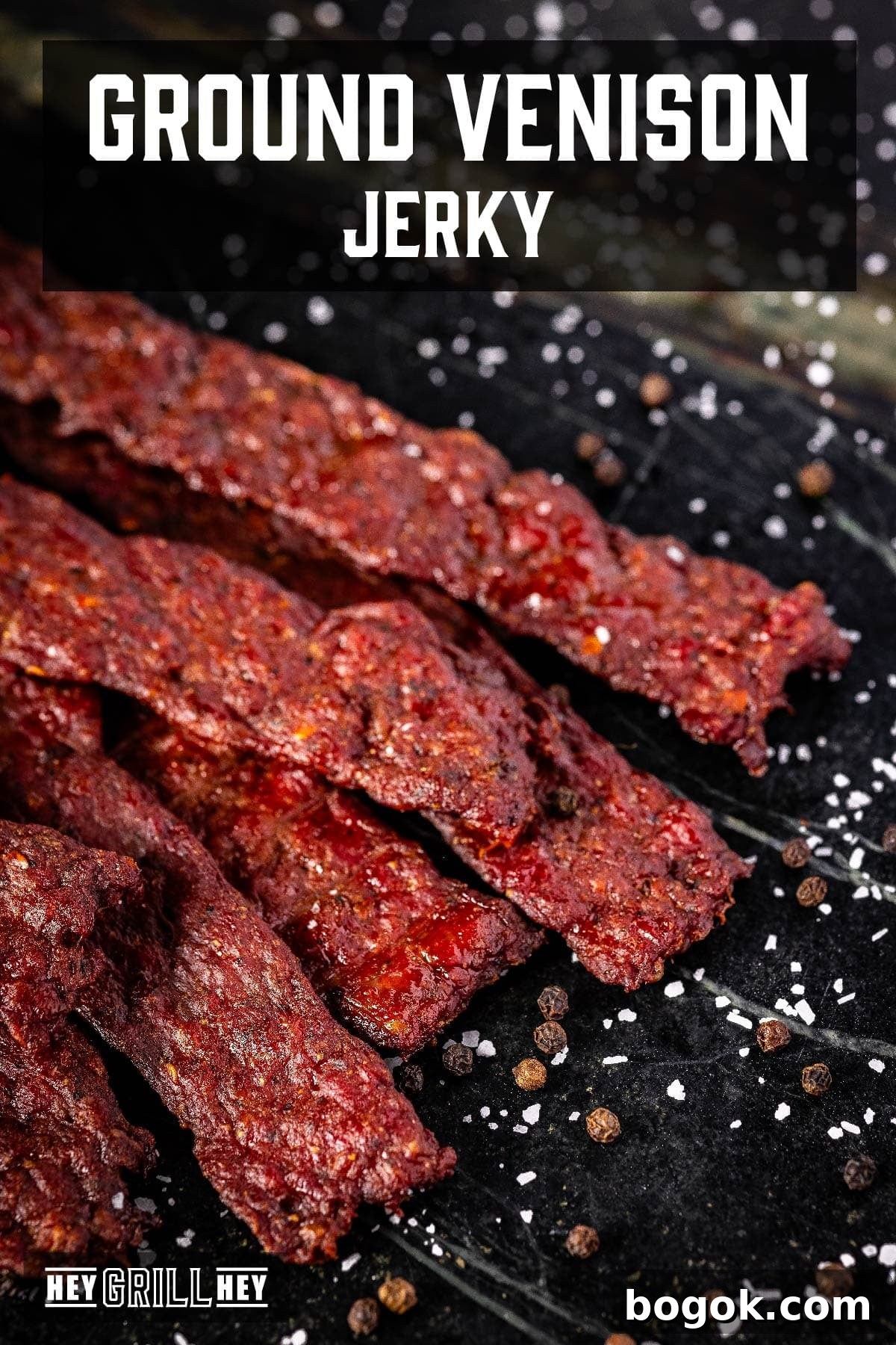 Jerky sticks on a black plate. The text overlay reads 'Ground Venison Jerky' at the top, and 'Hey Grill Hey' at the bottom.