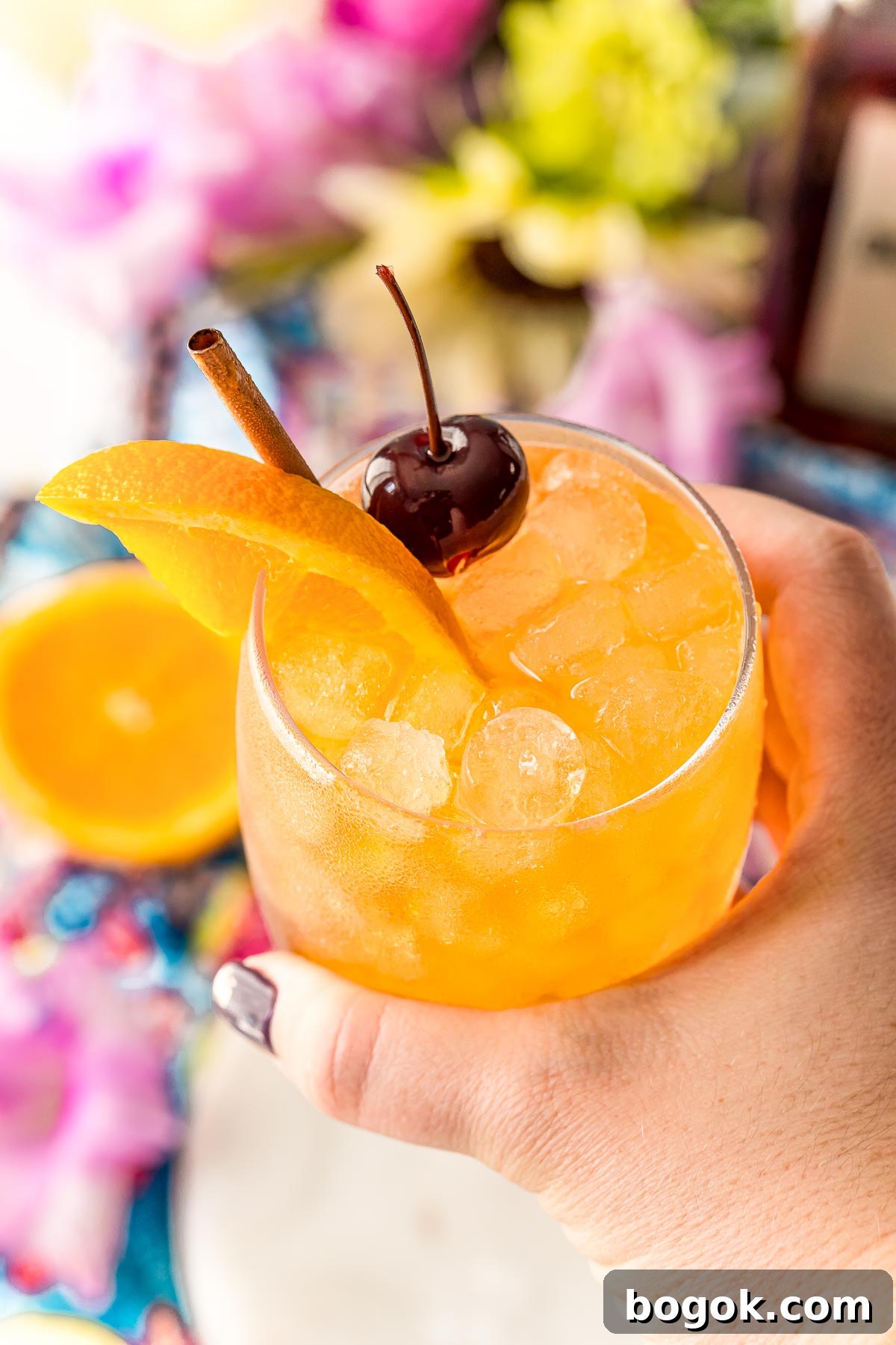 Classic Amaretto Sour Cocktail Recipe with a Citrus Twist 11 Woman's hand holding an Amaretto Sour up to the camera.