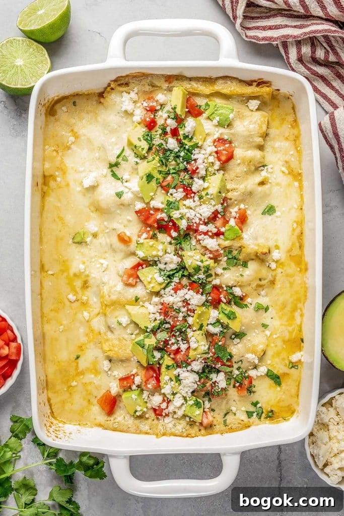 Top view of shrimp enchilada in a baking dish topped with cheese, diced tomatoes and avocados.