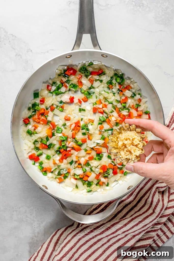 adding minced garlic to the sautéed veggies