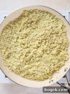 How to Make Cauliflower Rice at Home: Simple Step-by-Step Guide 9 A skillet filled with cooked riced cauliflower sits on a stovetop.