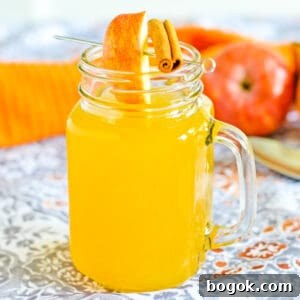 Boozy hot apple cider in glass mug garnished with apple slice and cinnamon stick