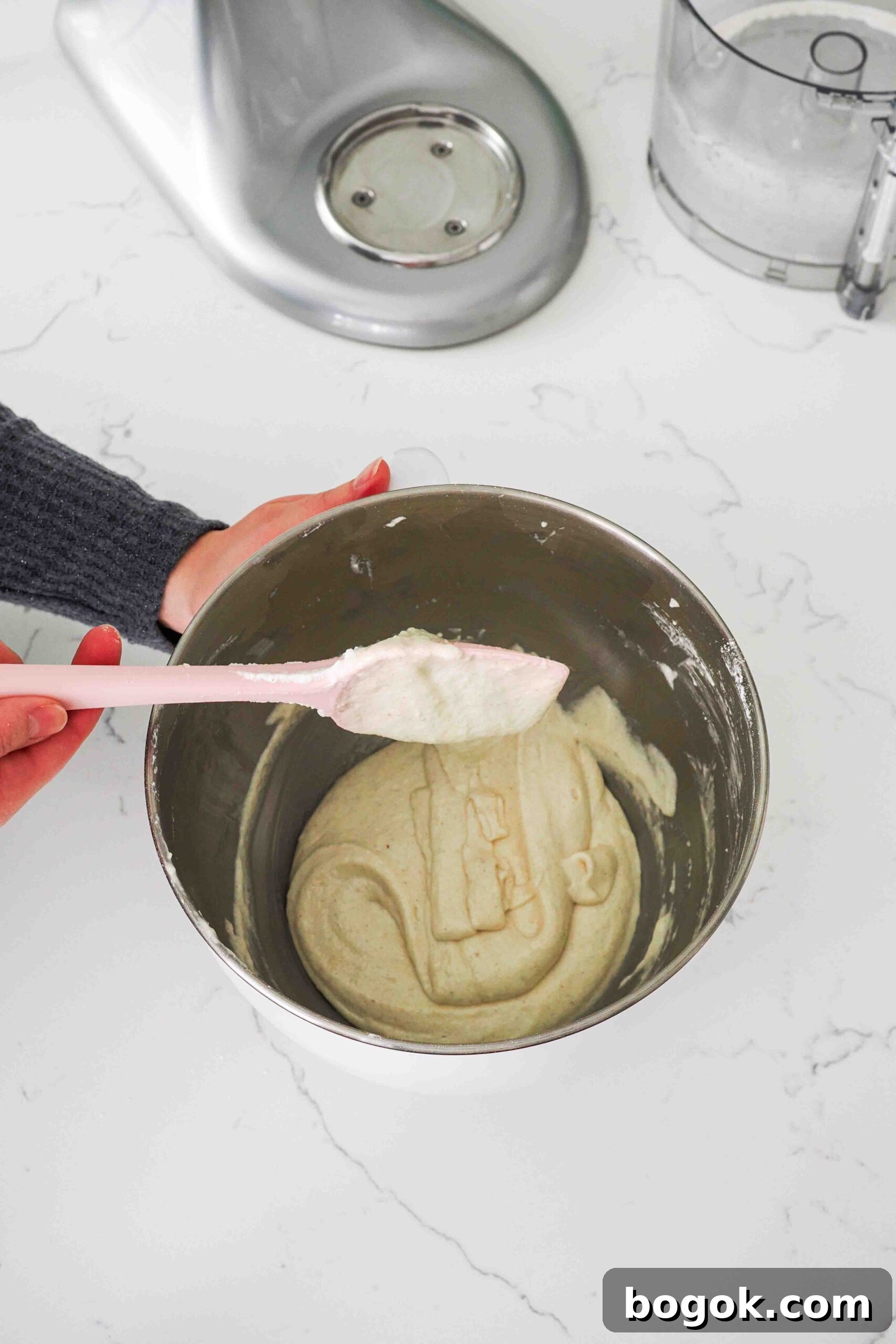 White Chocolate and Pomegranate Macarons — Recipe & Tips 10 Macaronaged batter flows off a spatula into a mixing bowl.