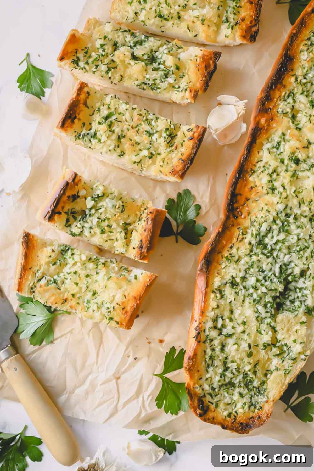 Garlic Bread Recipe with Crispy Herb Butter Crust 7 Pieces of garlic bread next to a whole loaf of baked garlic bread.