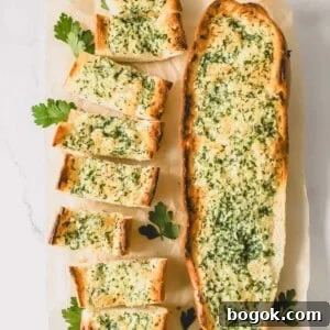 Garlic Bread Recipe with Crispy Herb Butter Crust 9 Two loaves of garlic bread topped with an herbed butter spread with one sliced into pieces.