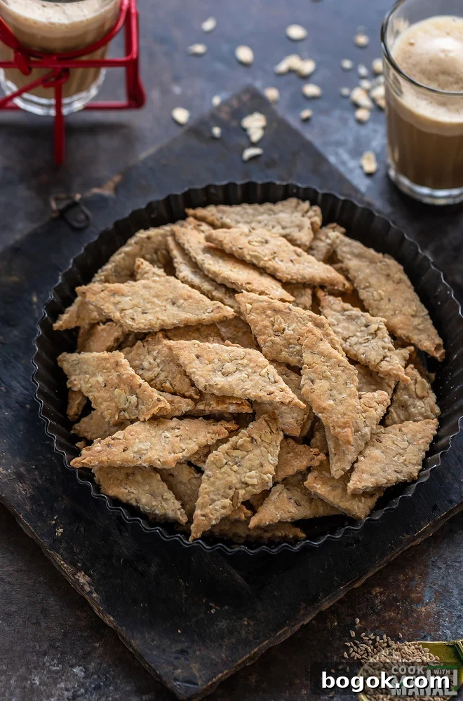diamond shaped oats namak pare placed in a round plate with glass of chai in the background