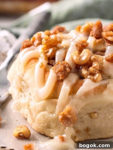 Baked Banana cinnamon roll with icing on plate with fork.