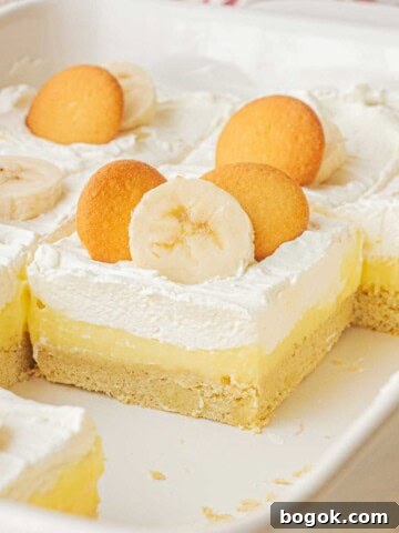 Baked slices of banana cream pie bars in white ceramic pan.