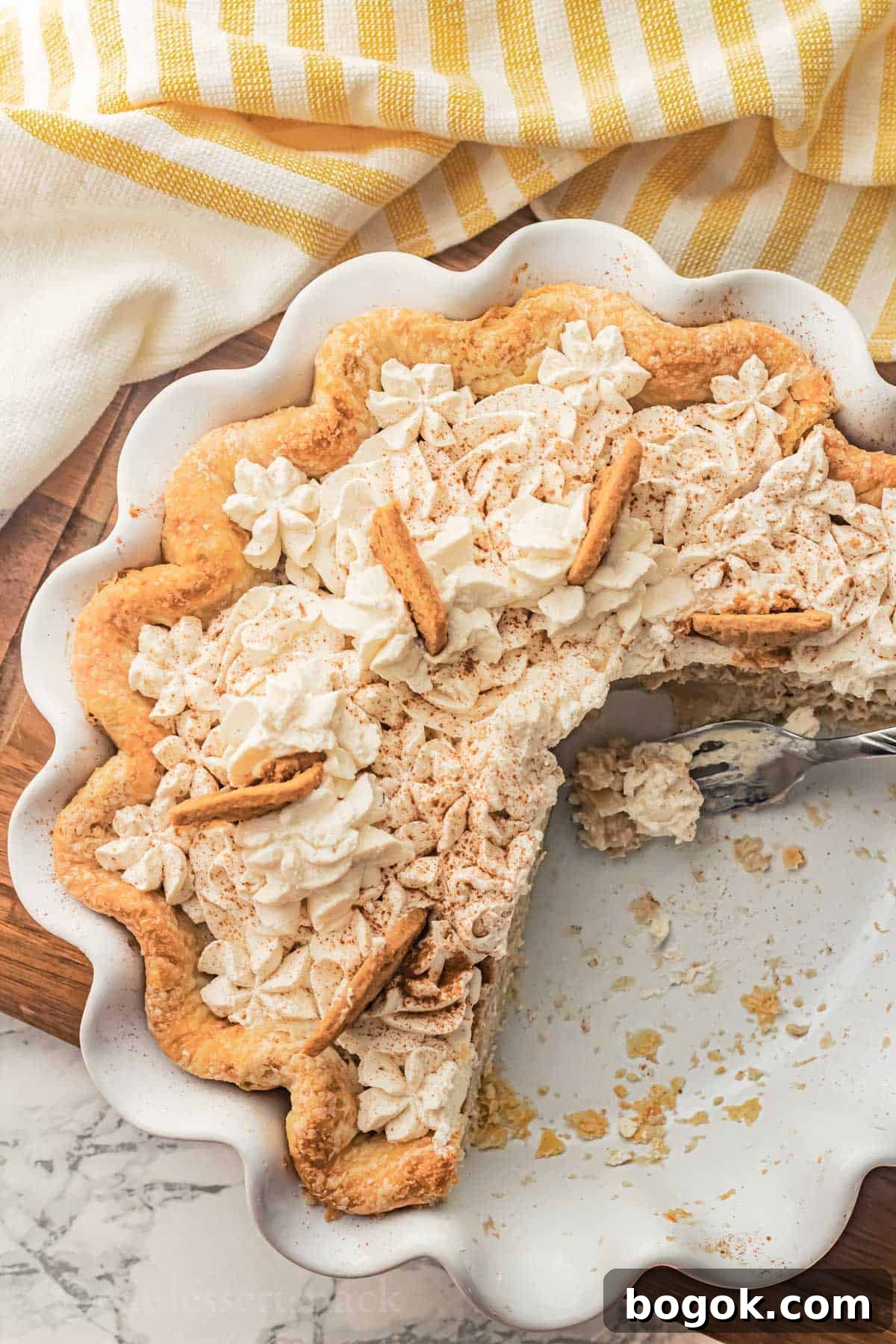 Baked banana pie with slices removed from white pan with bite of pie on fork resting in pie pan.