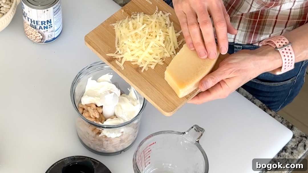 Garlic Parmesan White Bean Dip with Extra Protein 4 Adding shredded parmesan cheese to a chopper cup for the white bean dip.
