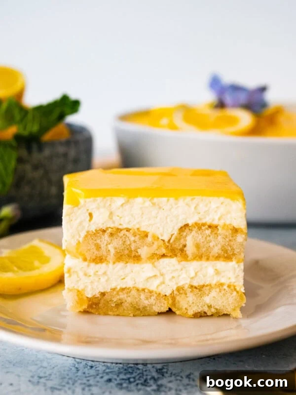 Slice of lemon tiramisu with lemon curd on a plate with a lemon slice.