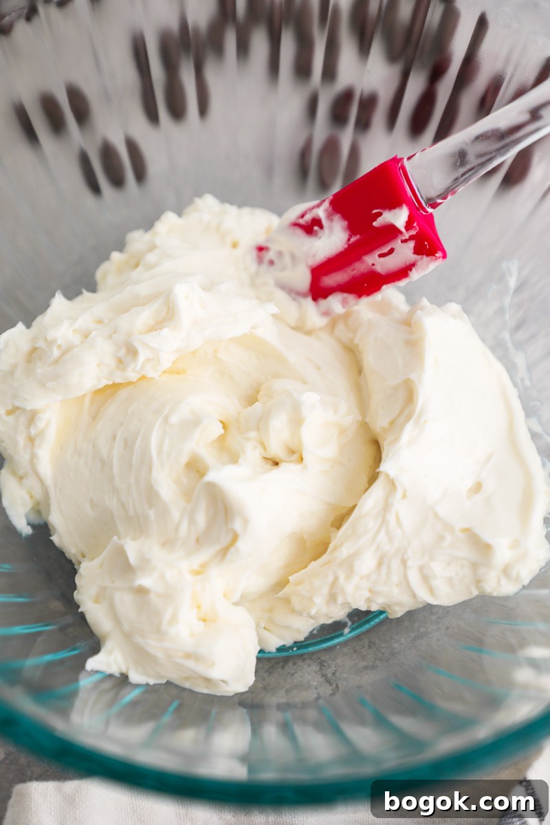 Whipped cream cheese filling made with cream cheese and powdered sugar sitting in a clear mixing bowl