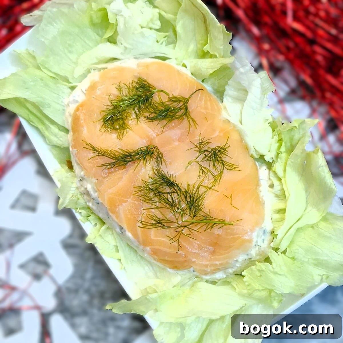An overhead shot of a salmon terrine turned out of the dish onto a bed of lettuce. The smoked salmon layer is now visible on top.