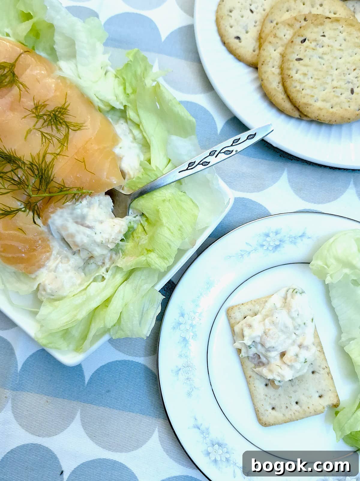 Salmon terrine being spooned onto a small square cracker.