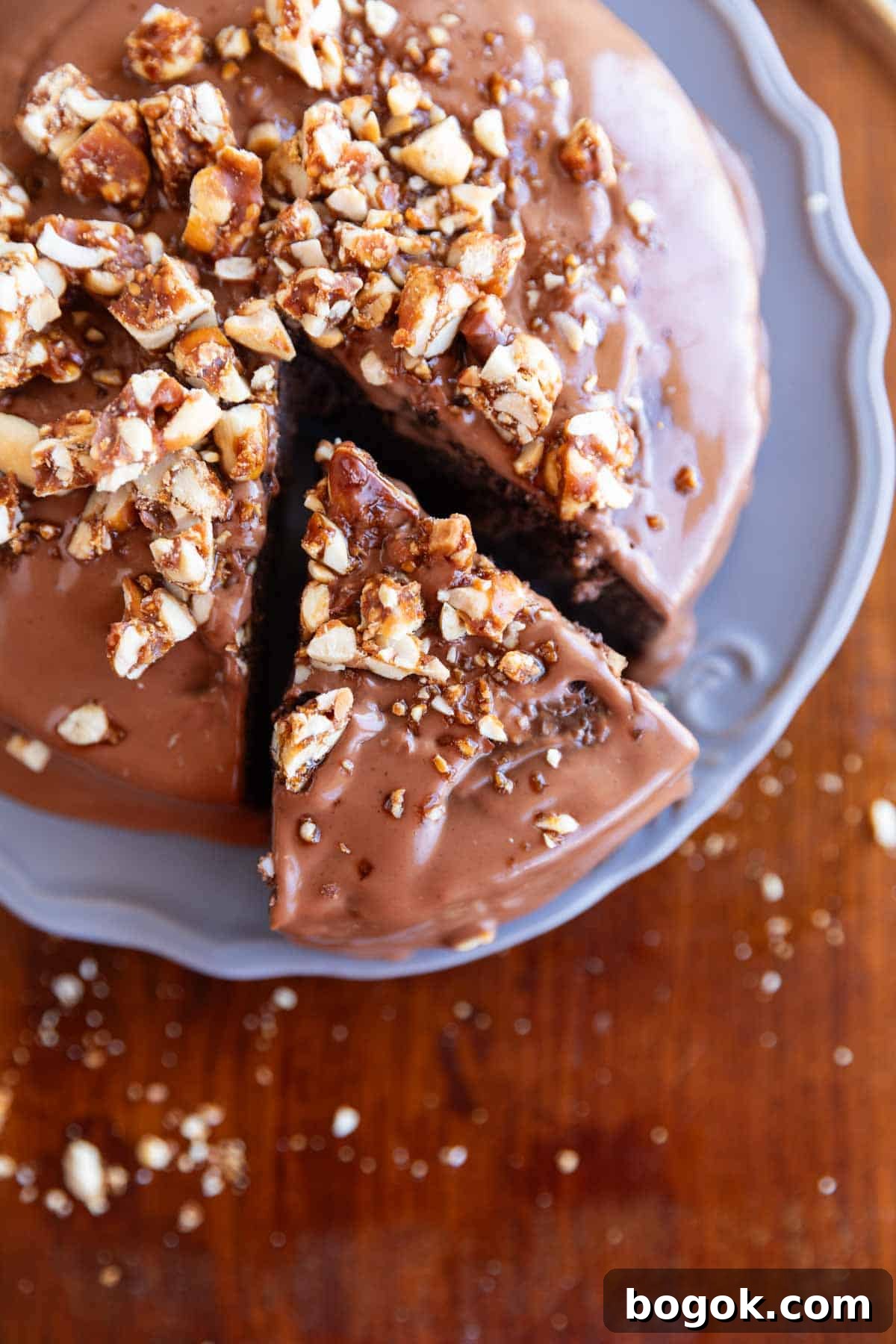 ragi chocolate cake with frosting and nuts sprinkled on top on a grey plate