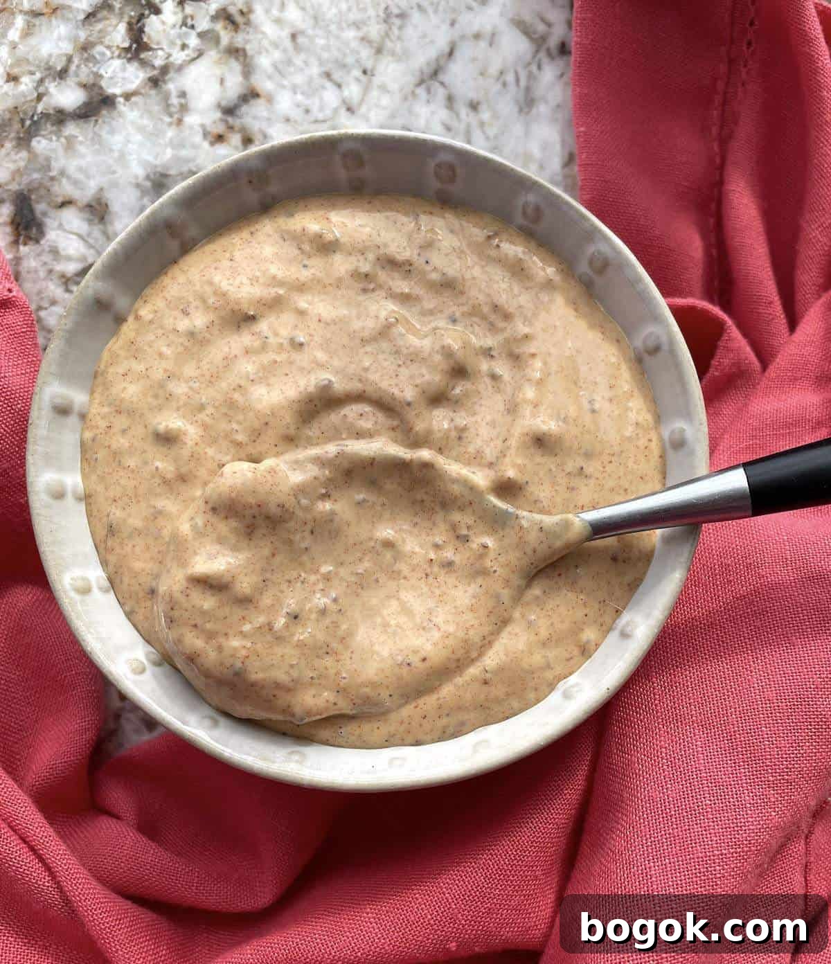A bowl of remoulade sauce with a spoon in it.