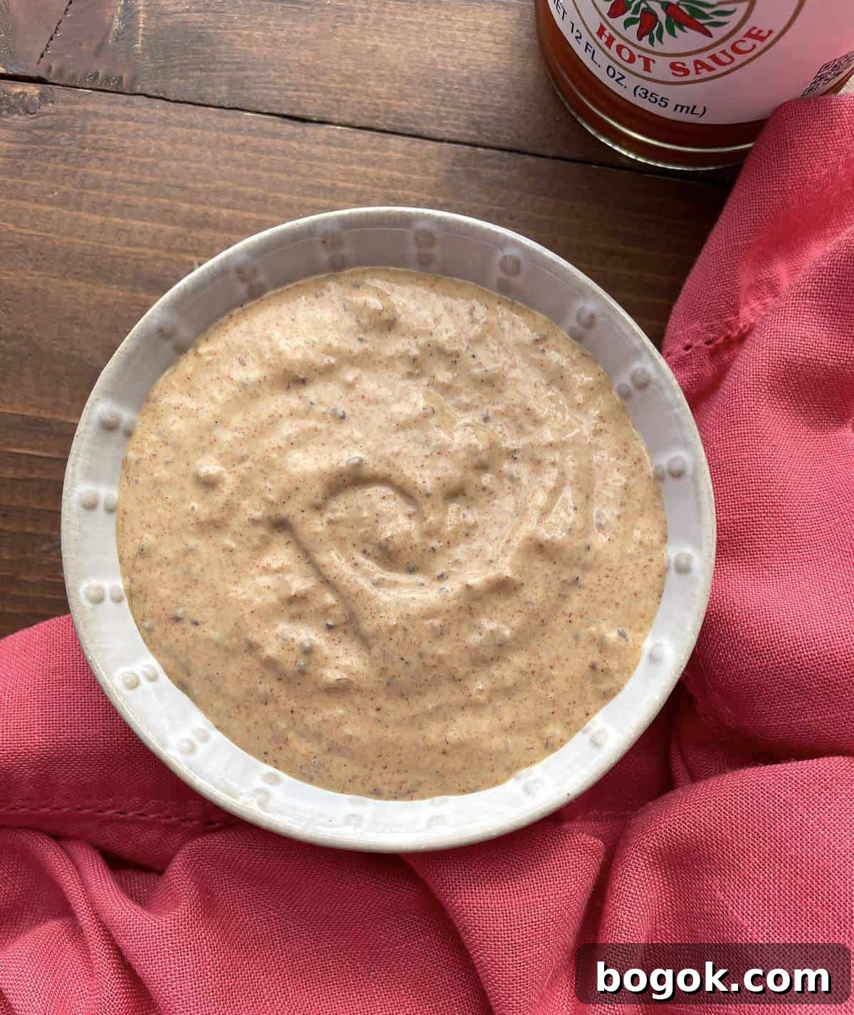 A small bowl of spicy creol remoulade with a bottle of Crystal hot sauce.