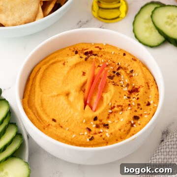 A white bowl of roasted red pepper hummus to serve as an appetizer.