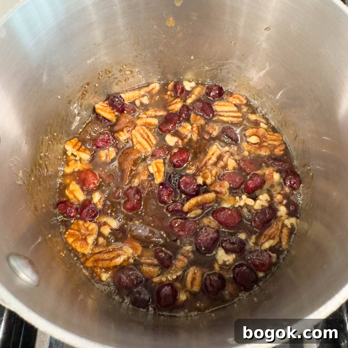 Fig jam topping with dried fruit and nuts simmering in a small pot