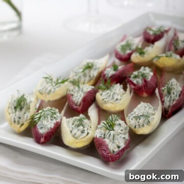 Belgian endive leaves filled with herbed cream cheese on a white platter.
