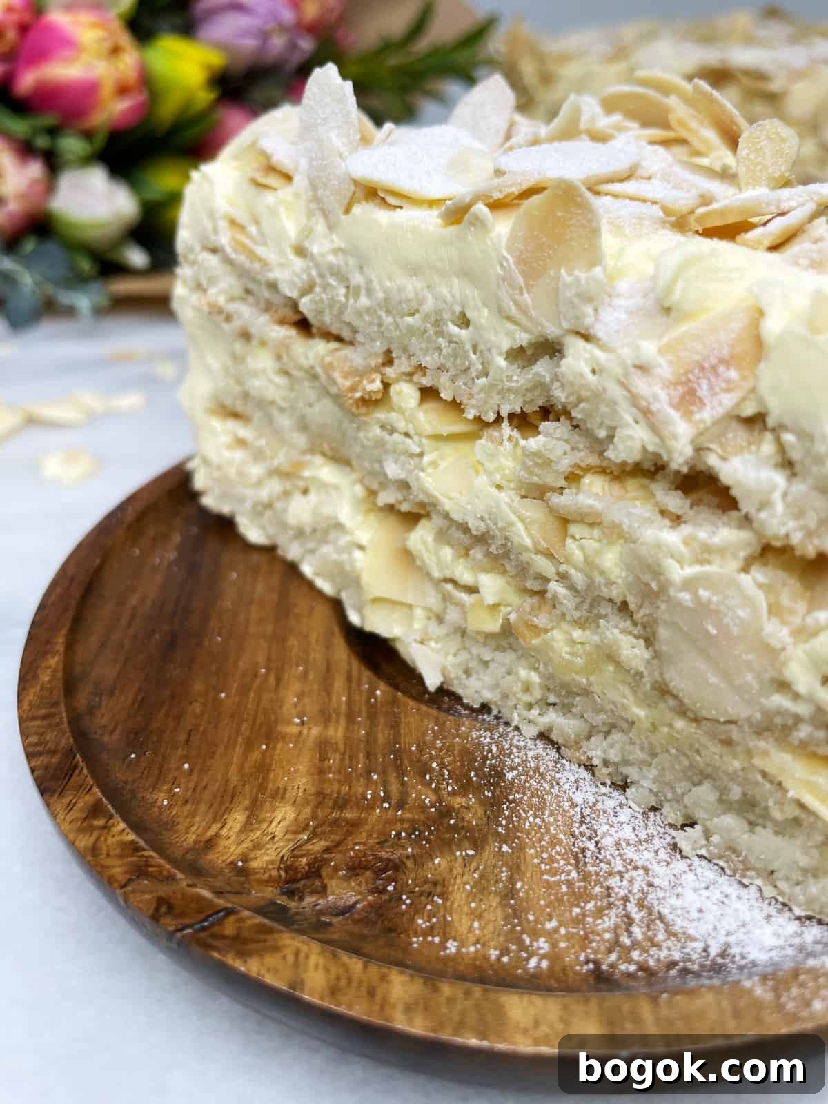 Authentic Gluten-Free Italian Almond Cake Recipe 4 A slice of almond cake on a wooden dessert plate with flowers in the background