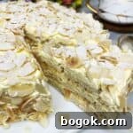 Sliced almond cake covered with flaked almonds on a white platter.