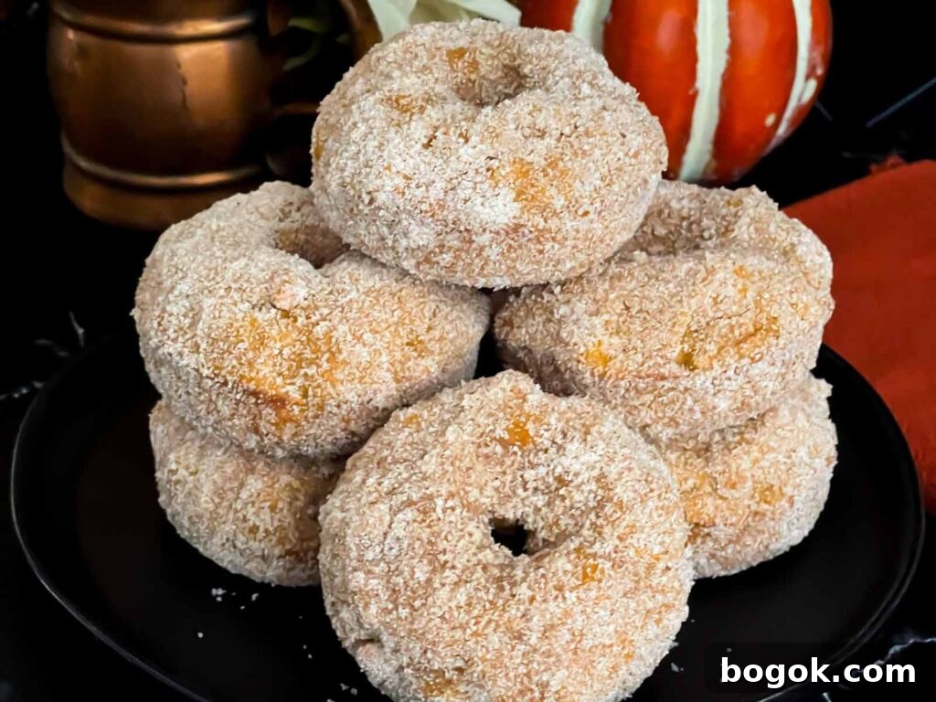 Baked pumpkin donuts stacked on a dark plate.