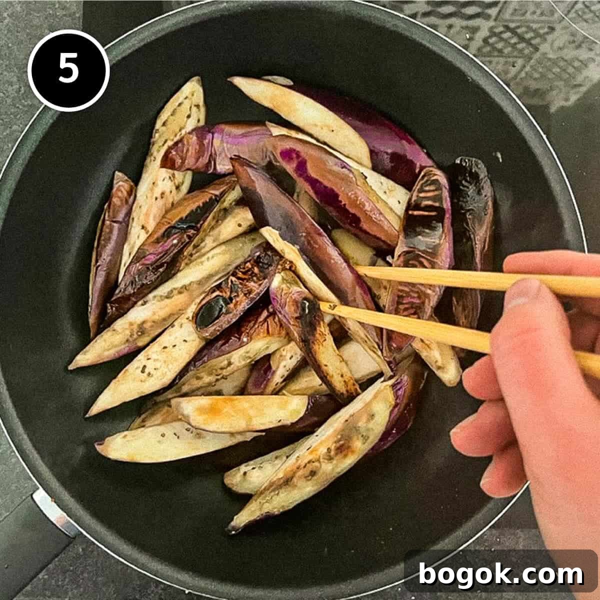 Frying eggplant in a wok until lightly charred.